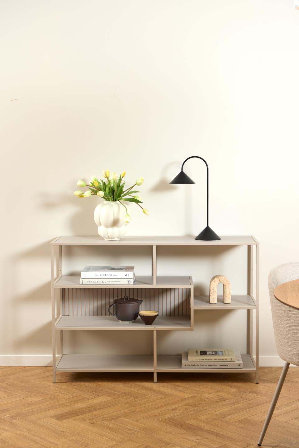 Modern bookshelf with decorative items against a plain wall