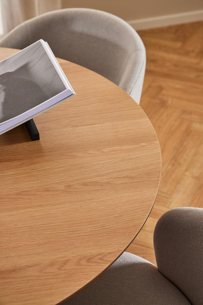 Round wooden table with two gray chairs in a room with wooden flooring.