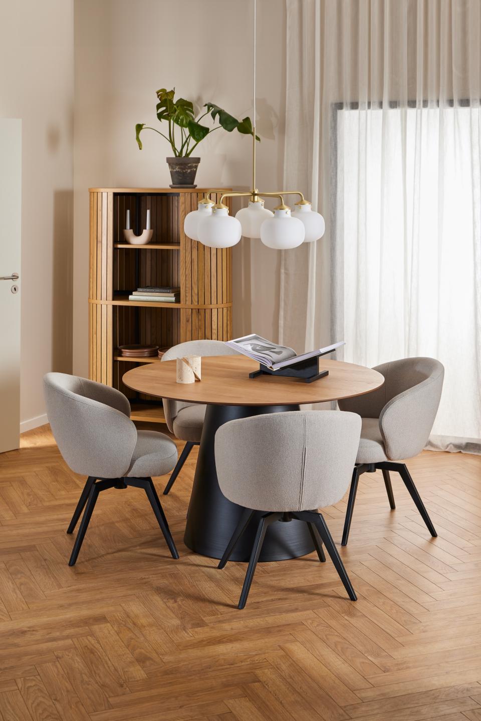 Modern dining area with round Soli table and chairs in a well-lit room.