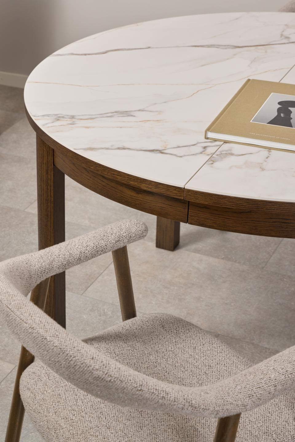 Round ceramic Southampton dining table with wooden legs and a chair in front on a tiled floor