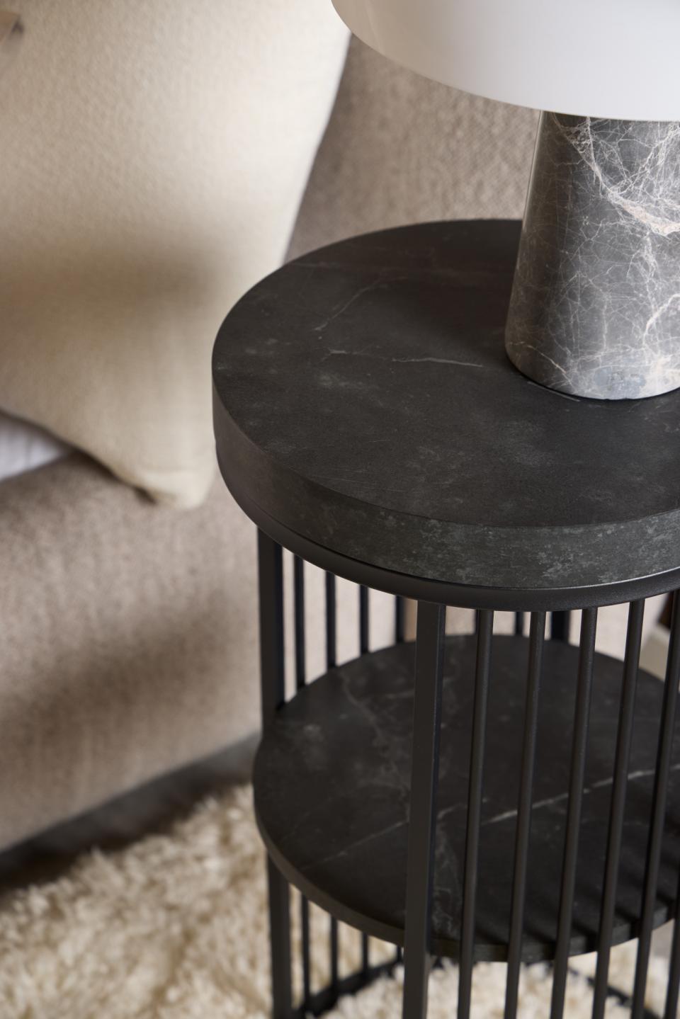 Black metal side table with marble-like top next to a sofa