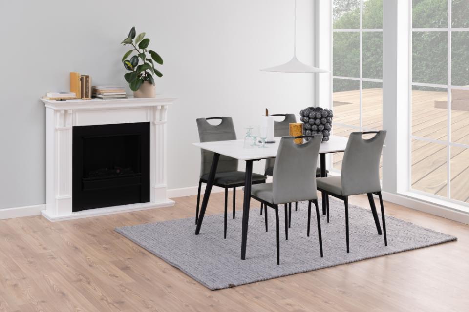 Dining room with a table and chairs in front of a fireplace.