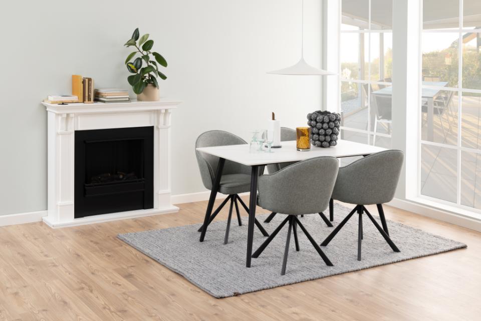 Dining area with a table and chairs in a room with a fireplace and large windows.