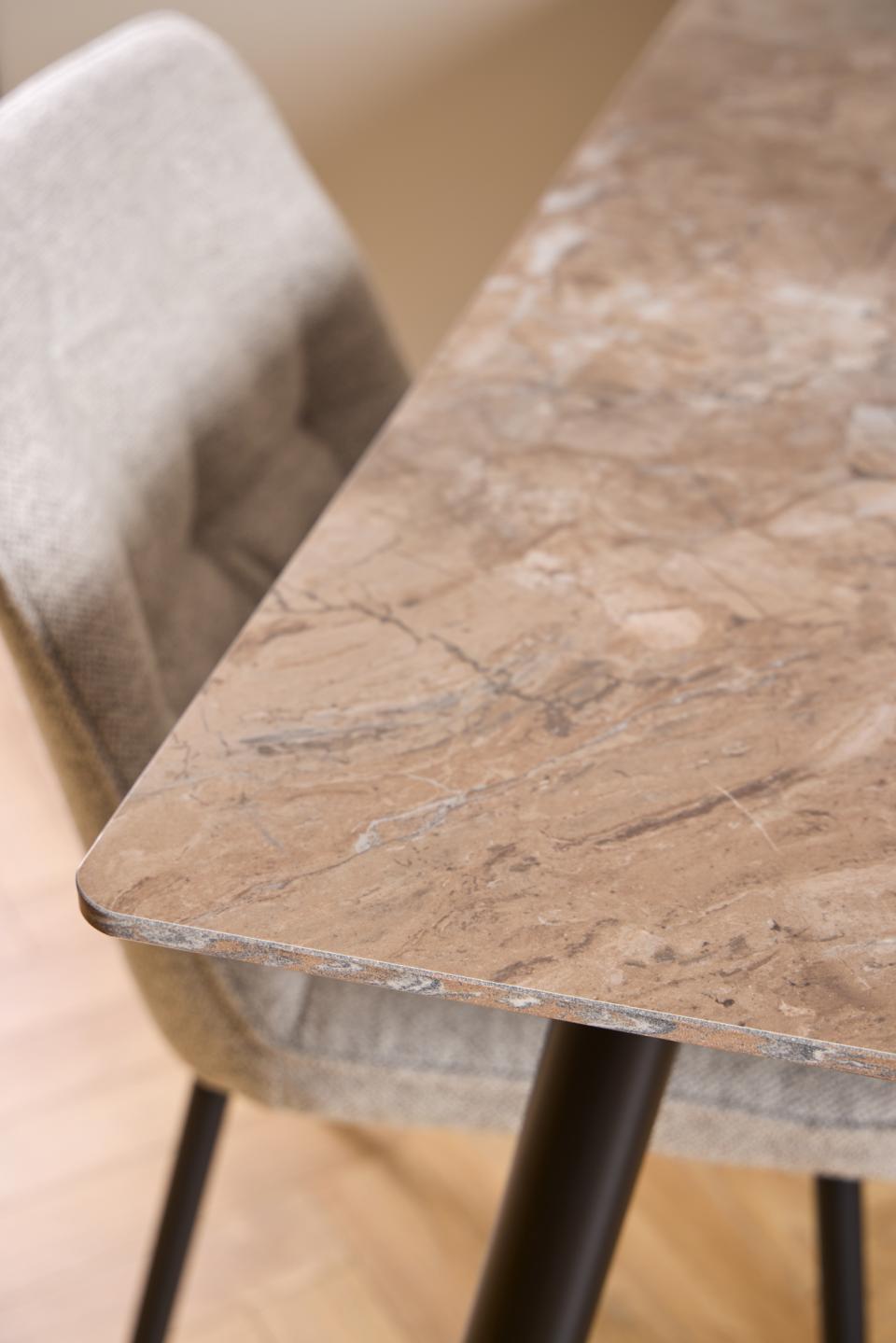 Close-up of a rectangular dining table with a brown and beige marble-look top, shown with a gray upholstered chair on a light wood floor.