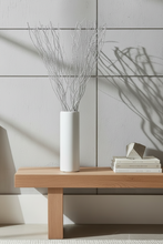 Load image into Gallery viewer, White vase with dried branches on a wooden table against a tiled wall.
