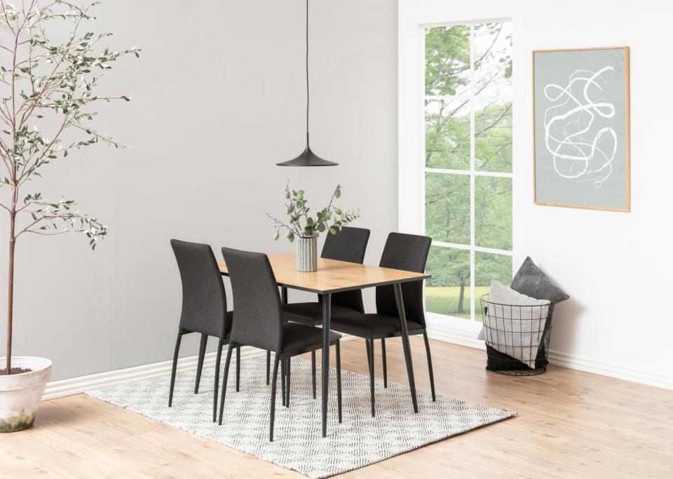 Dining room with a wooden table and black chairs on a patterned rug.
