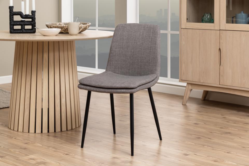 a becca grey fabric chair with black legs in a modern dining room with wooden table and flooring