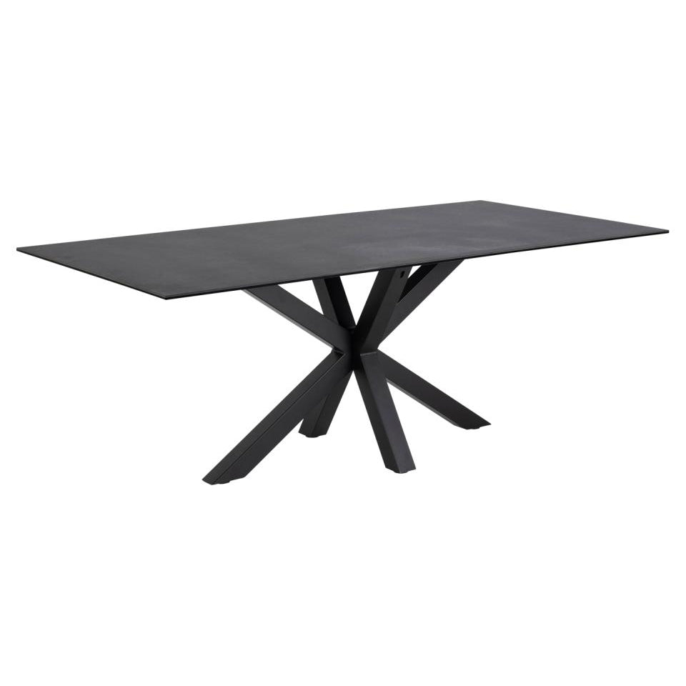 A large black ceramic dining table with a matte finish and a sculptural metal base.
