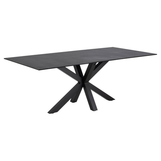 A large black ceramic dining table with a matte finish and a sculptural metal base.