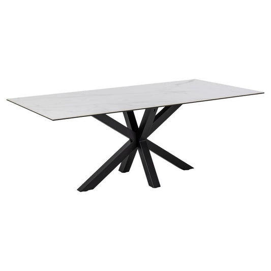 A large white rectangular dining table with a ceramic tabletop and a matt black metal cross base.